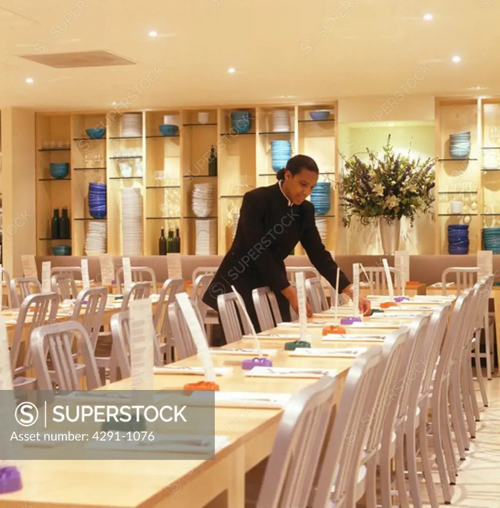 Waiter setting tables at modern London restaurant designed by Terence Conran