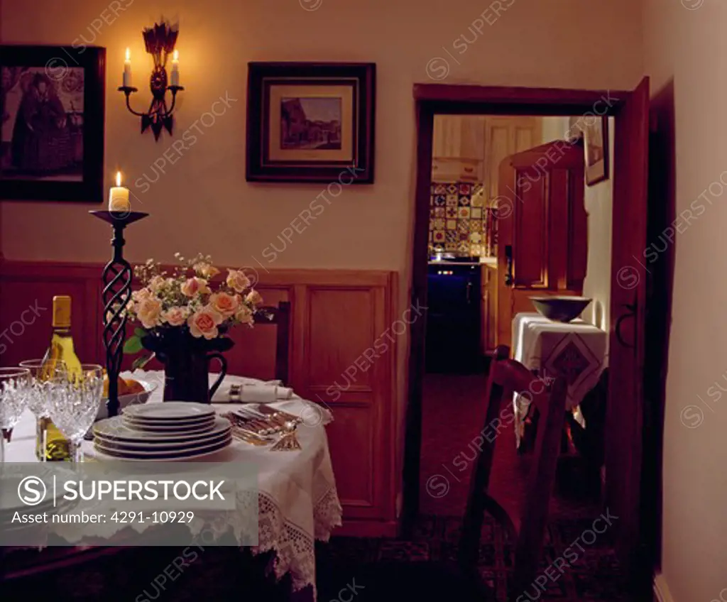 White cloth on table set for diner in country dining room with door open to kitchen
