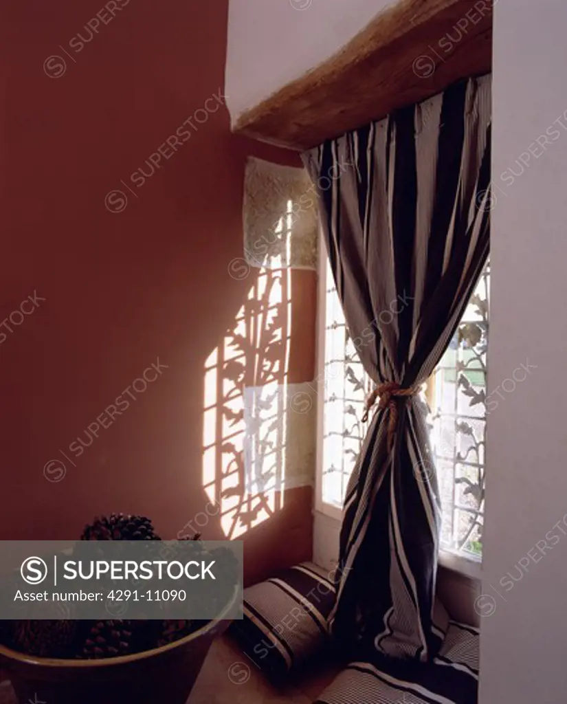 Pinecones in large earthenware bowl in front of window with striped curtain