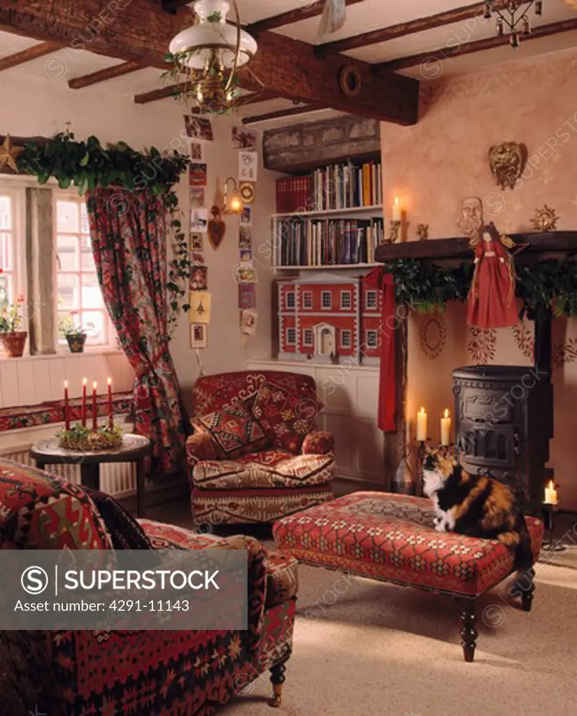 Red armchairs and stool in cottage living room decorated for Christmas