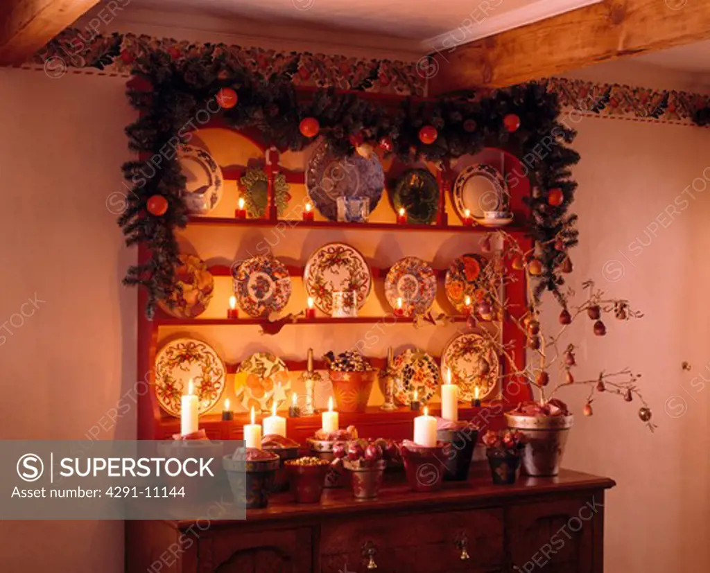 Christmas garland on shelves above sideboard with lighted candles