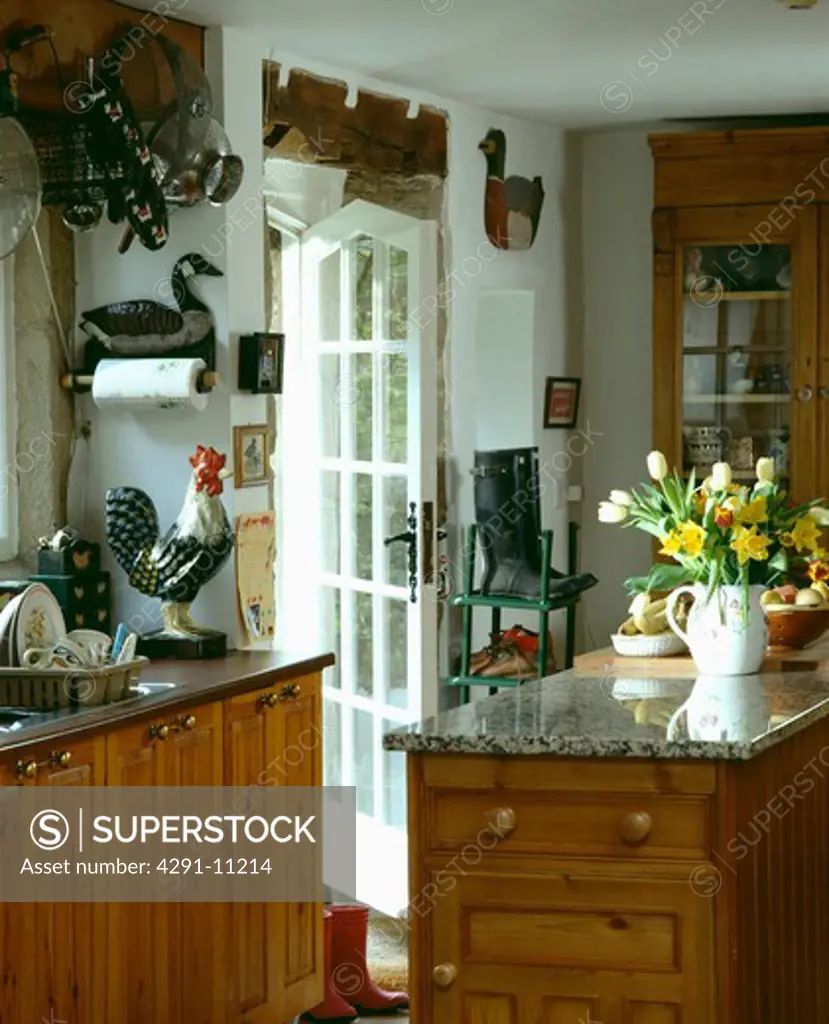 Granite worktop on island unit in country kitchen with ceramic chicken ornament