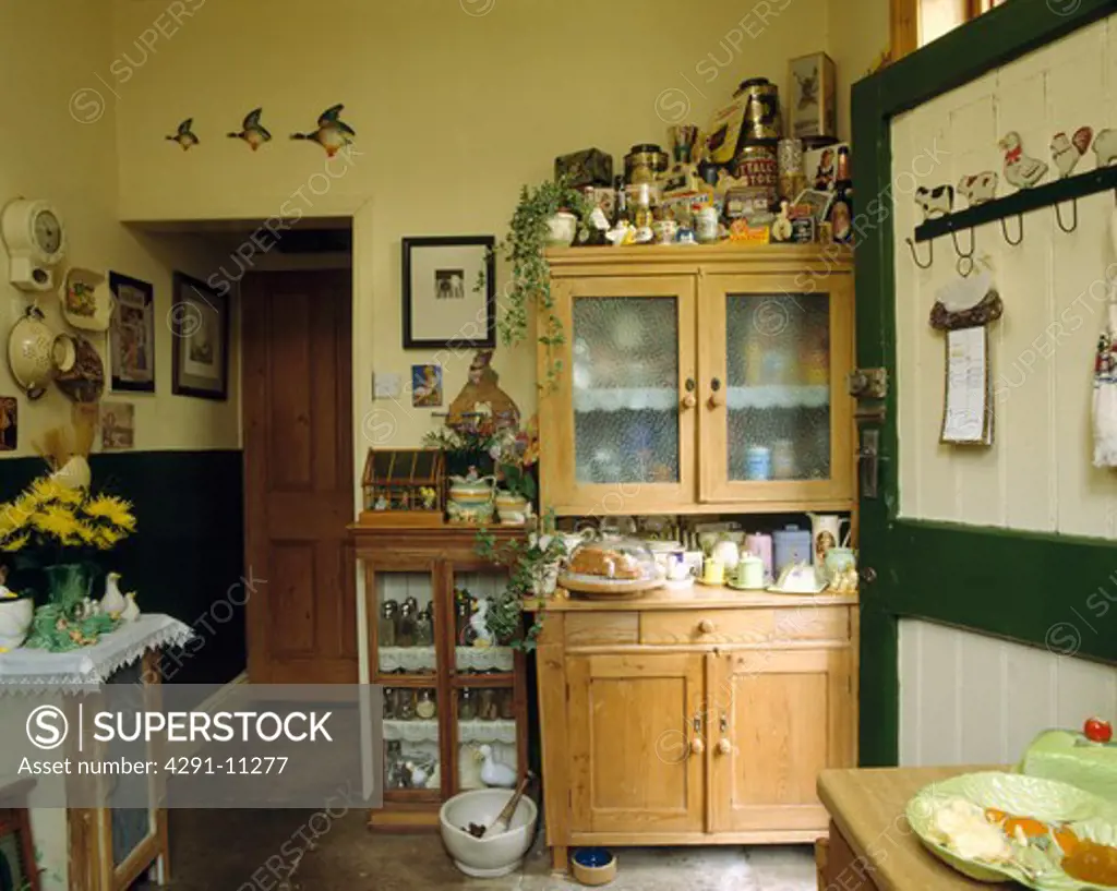 Fifties dresser piled with crockery in cluttered kitchen with flying ducks over doorway
