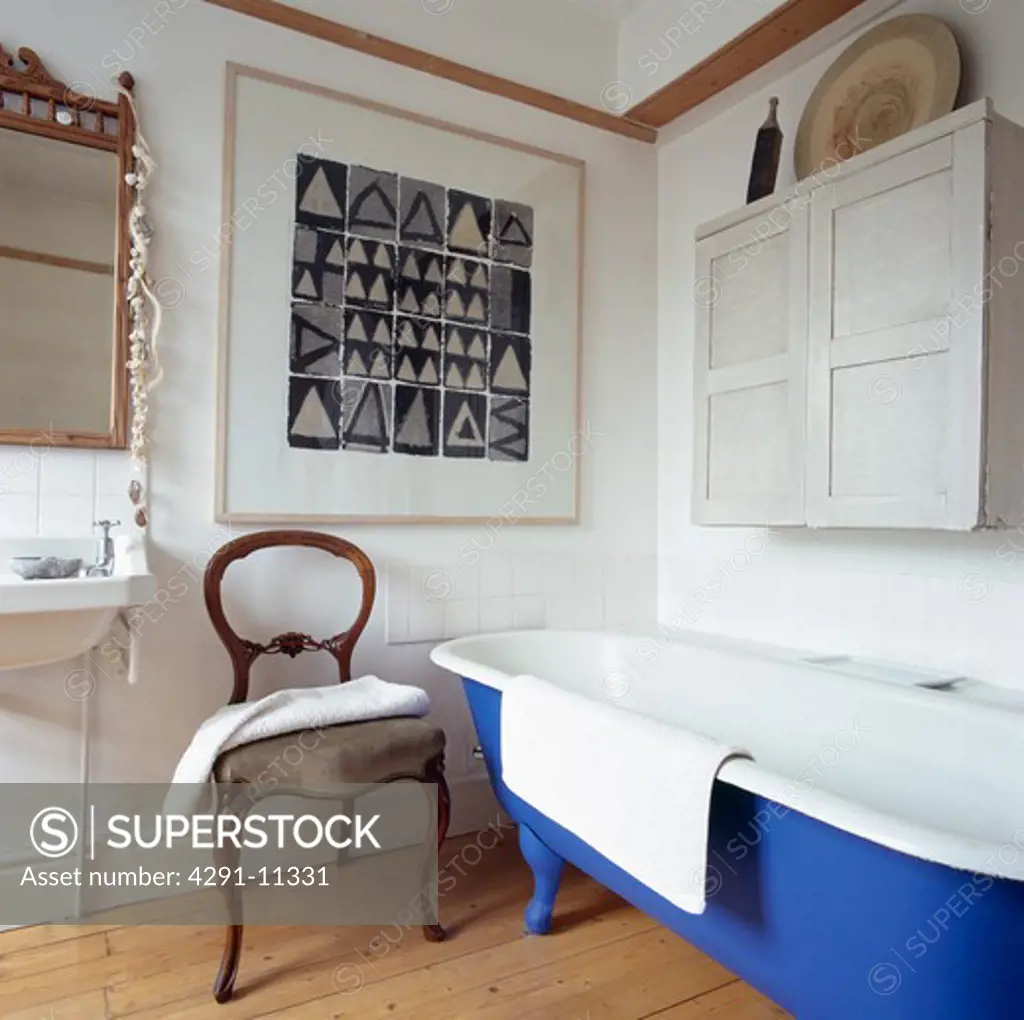 Black and white picture in small white bathroom with antique chair and rolltop bath