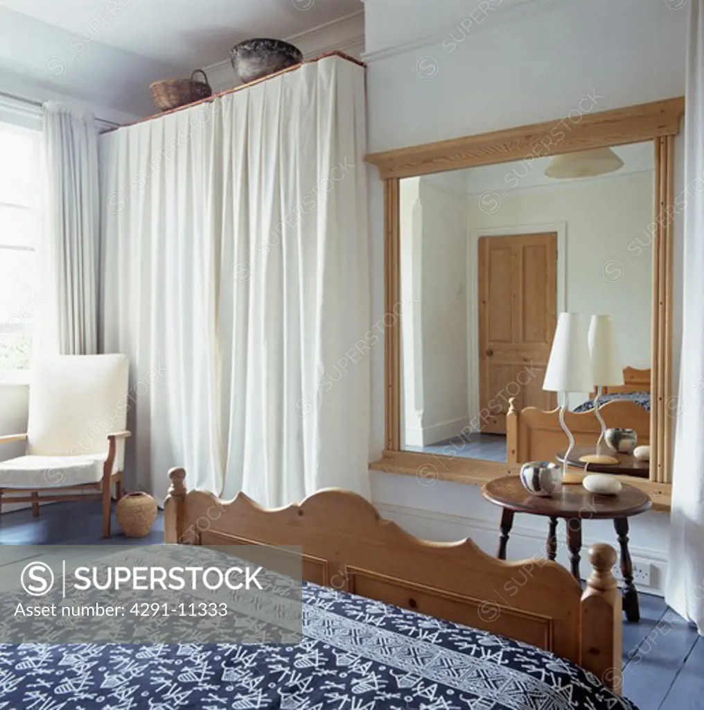 White curtained storage and large mirror in traditional bedroom