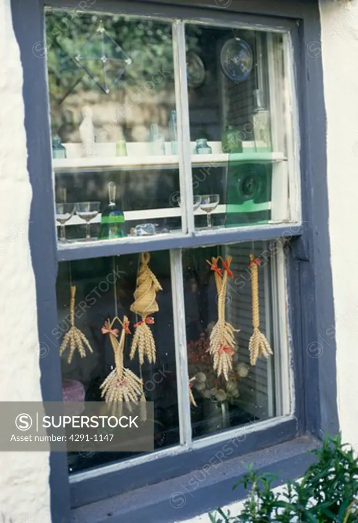Corn dollies hanging in blue sash window
