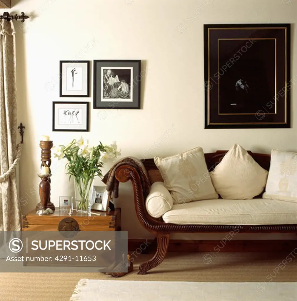 Group of pictures on wall above antique sofa and wooden chest