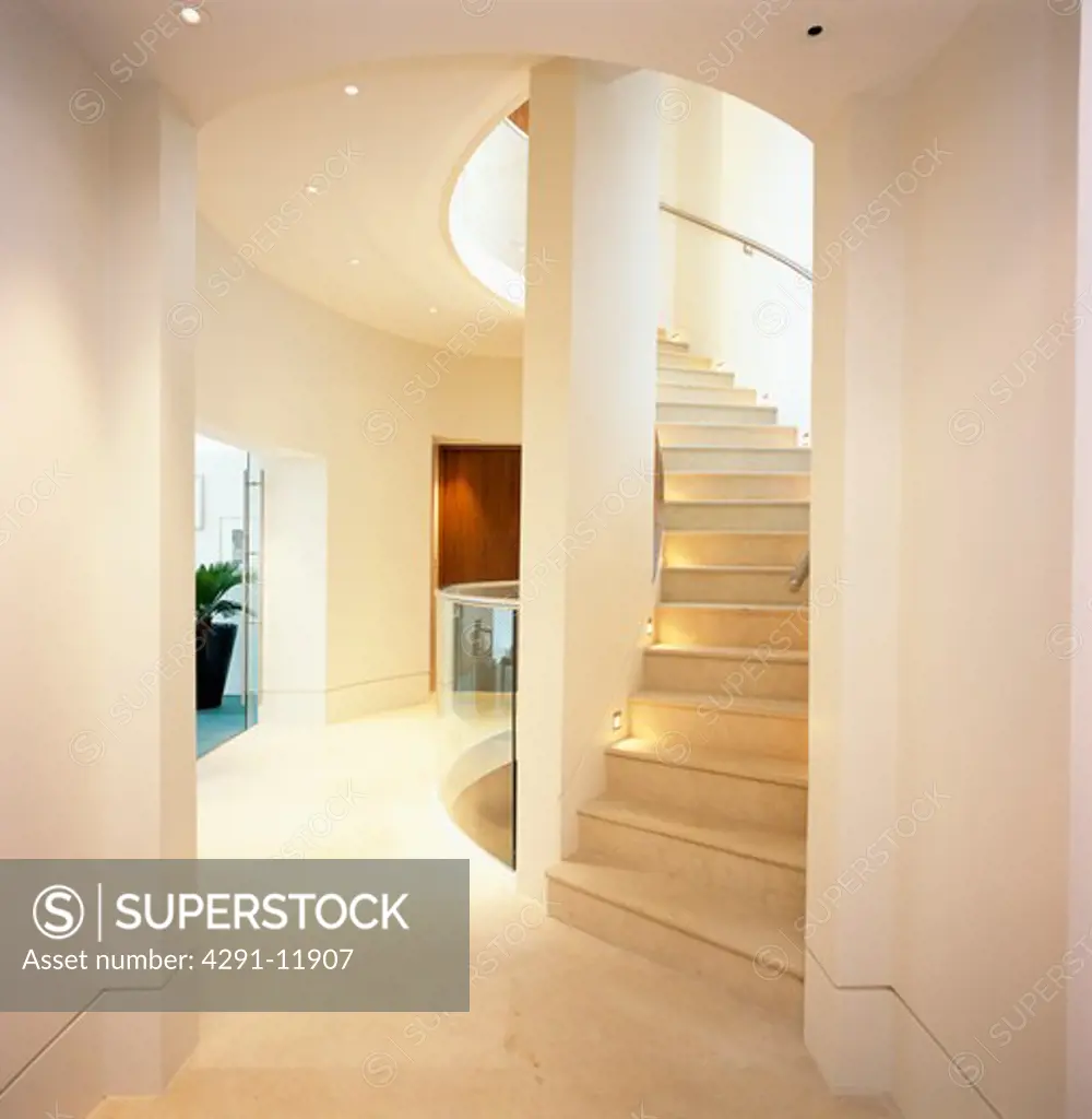 Curved wooden staircase in modern white hall