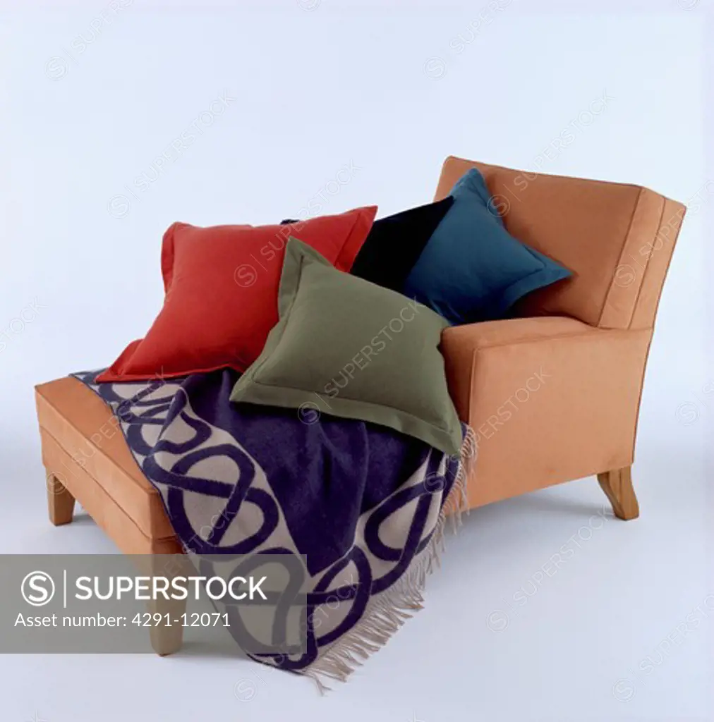 Close-up of chaiselongue with assorted cushions and patterned throw