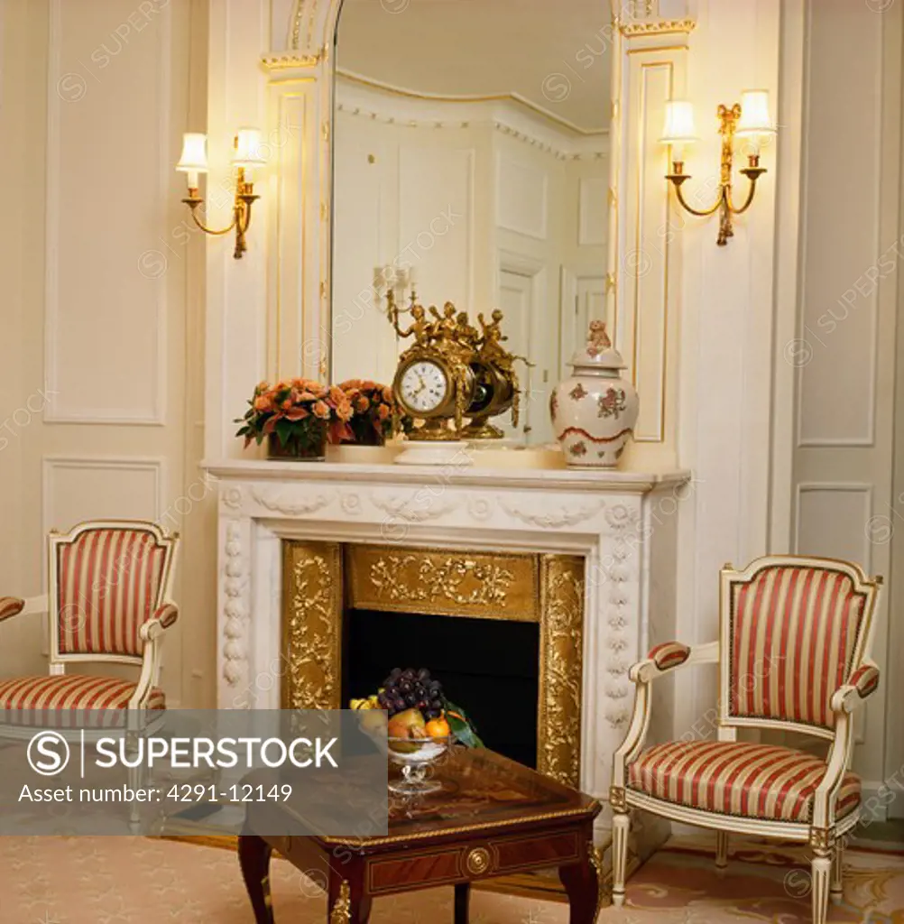 Striped upholstered 17-century-style chairs on either side of fireplace in townhouse living room