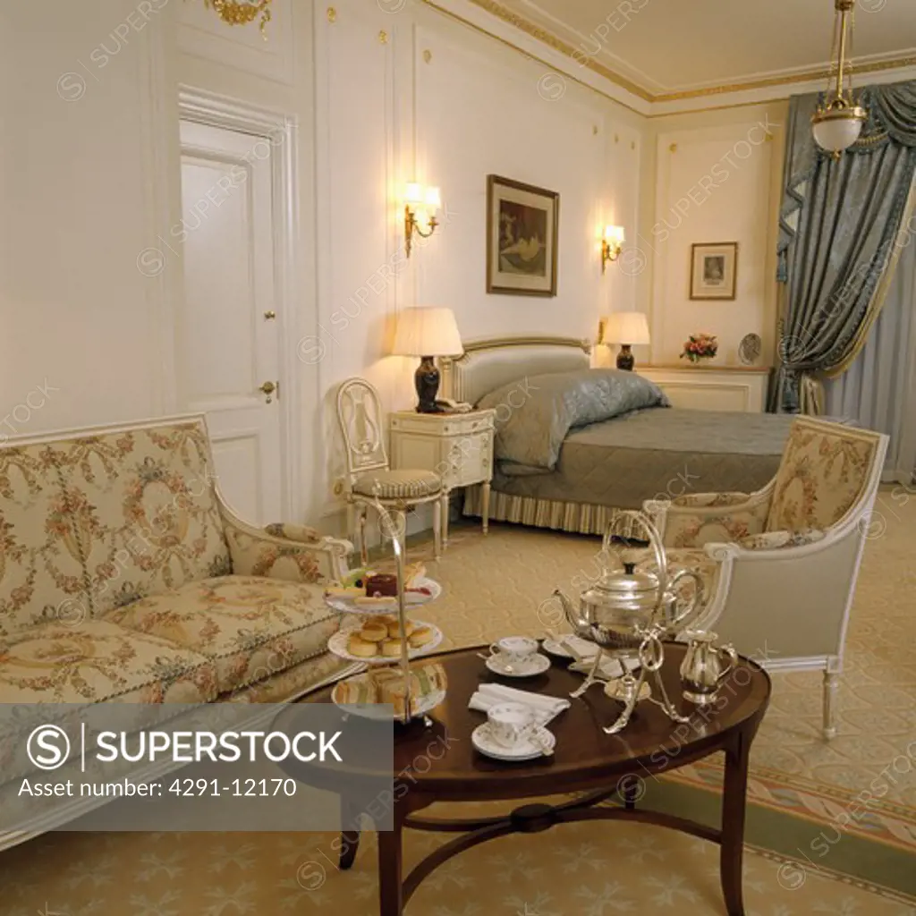 Silver teaset with samovar on table in large townhouse bedroom with 17th century-style sofa and armchair