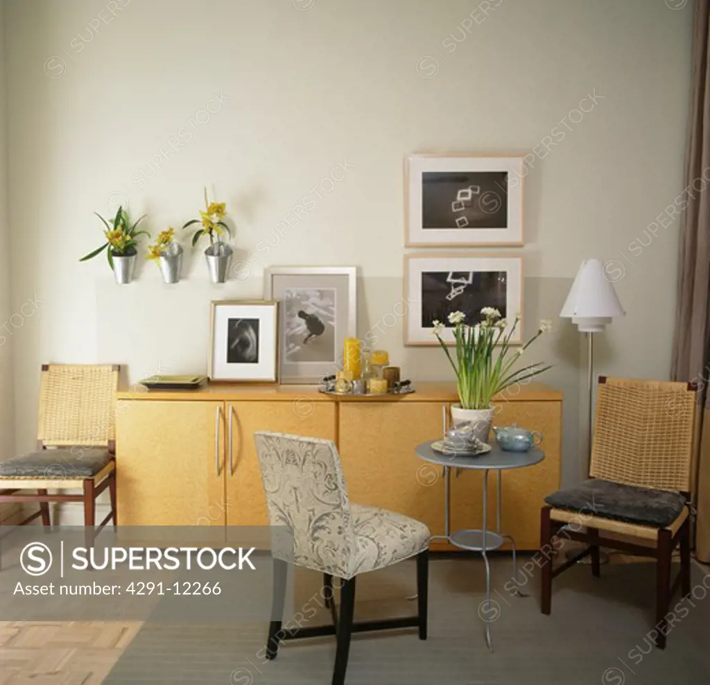 Pale wood sideboard and small table with upholstered chairs in apartment dining room