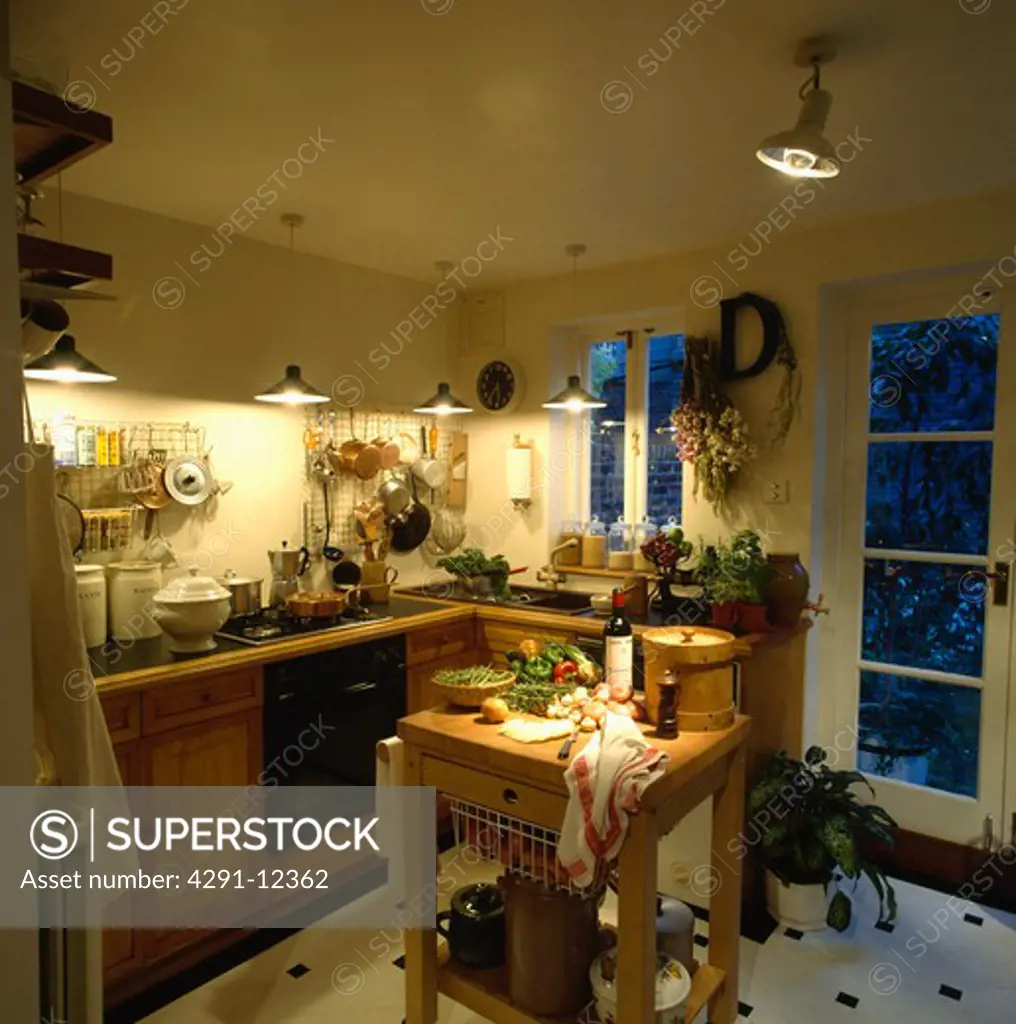 Pendant lighting in small kitchen with vegetables and plywood steamer on old butcher's block in centre of the room