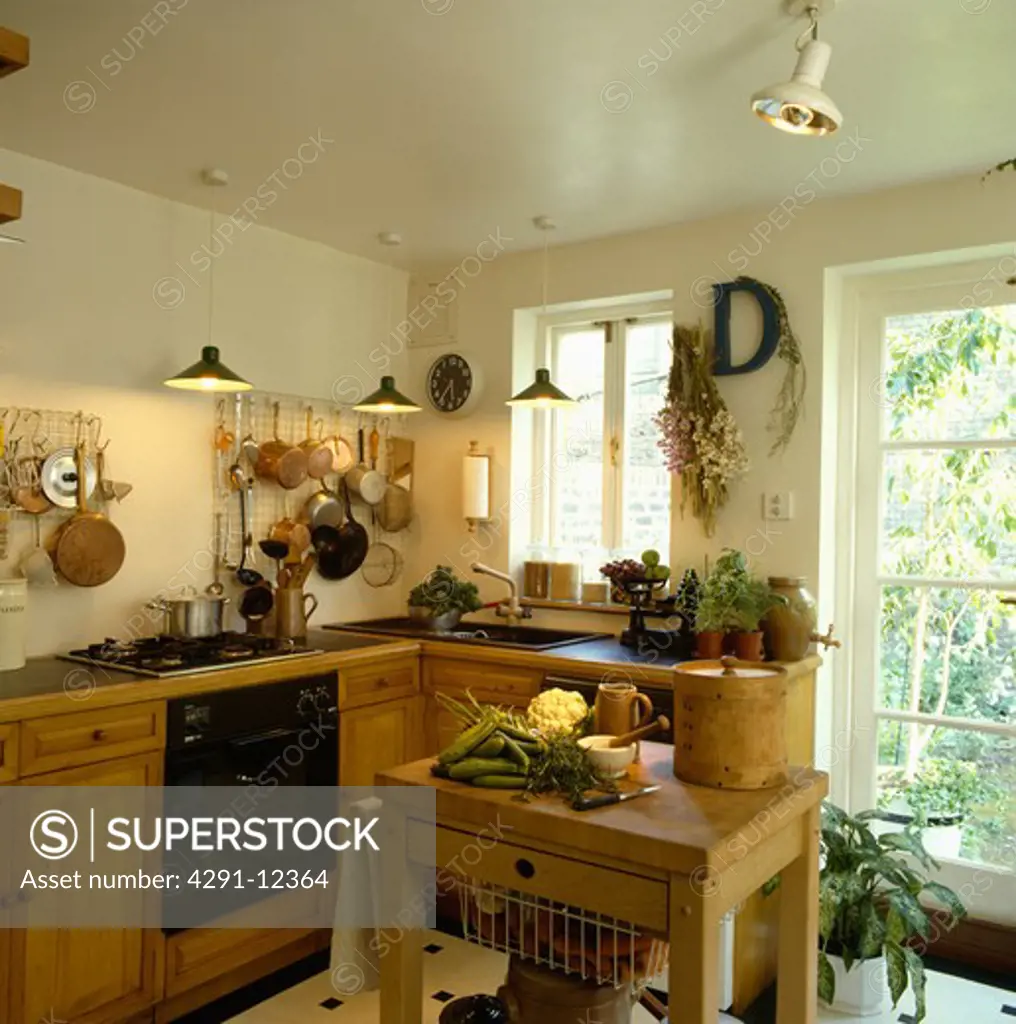 Pendant lighting in small kitchen with fitted wooden cupboards and butcher's block