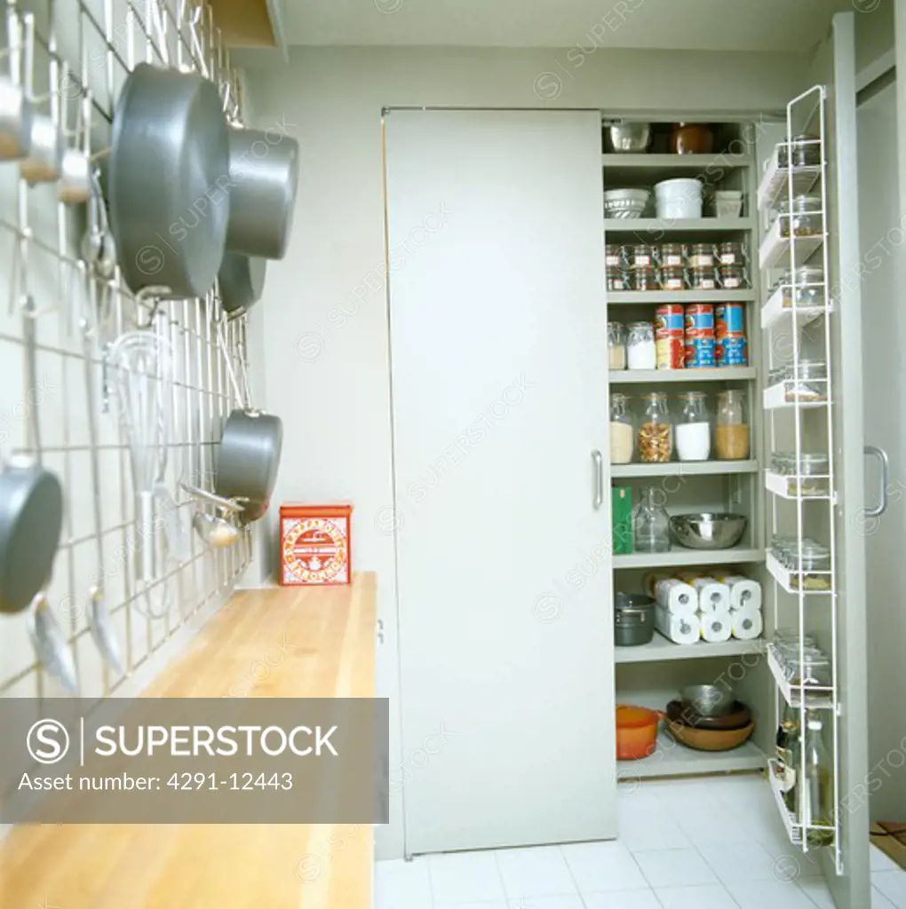 Modern galley kitchen with larder cupboard door open to storage shelves