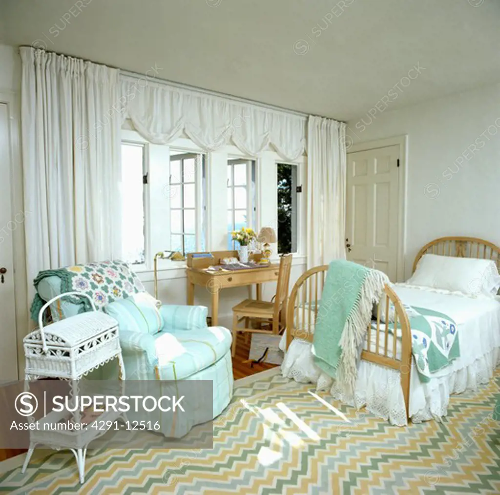 White curtains and striped turquoise armchair in coastal bedroom with ziz-zag striped carpet and single wooden bed