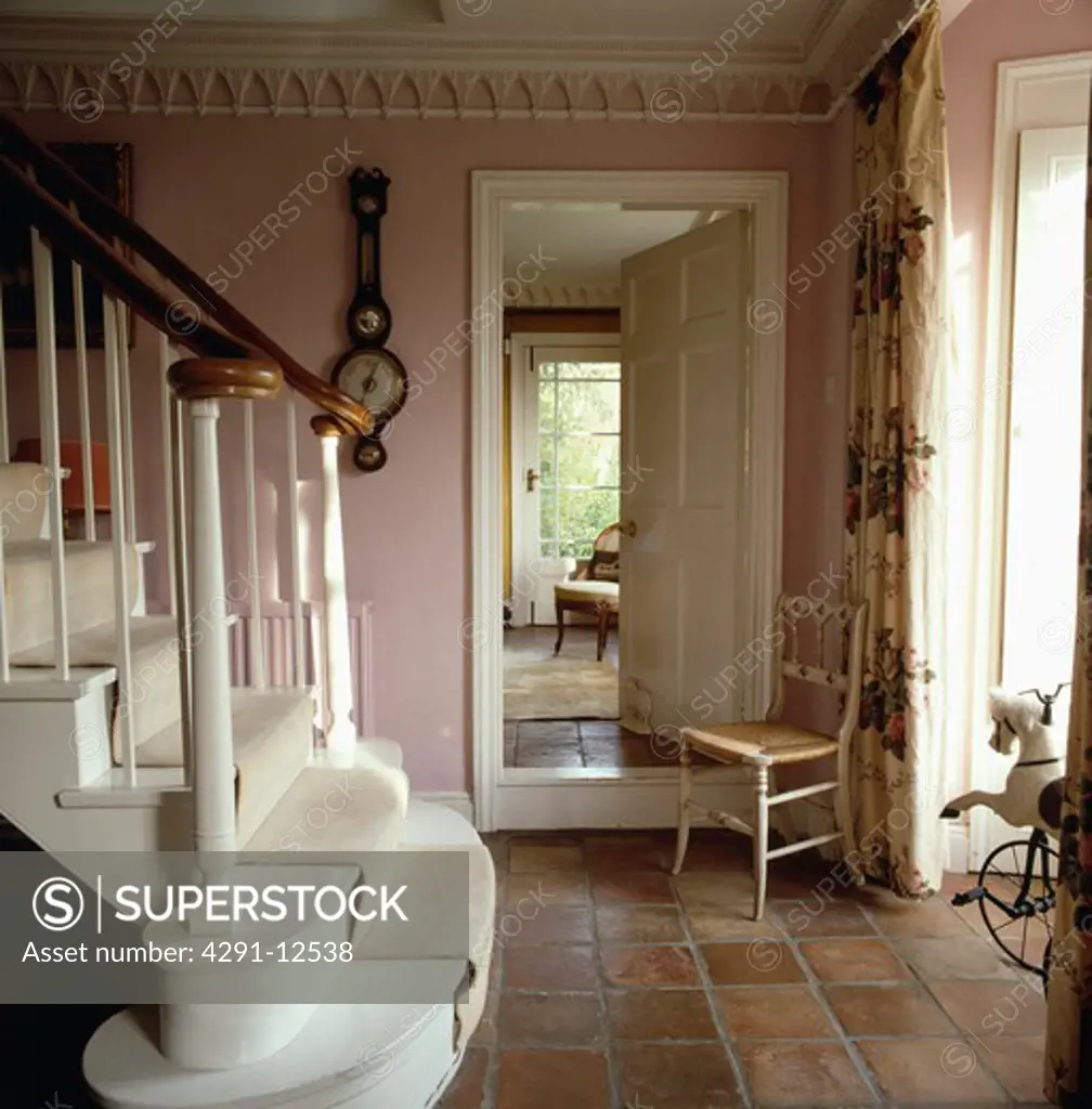 Gothic cornice and small Gothic chair in pink country hall with terracotta tiled floor and white staircase