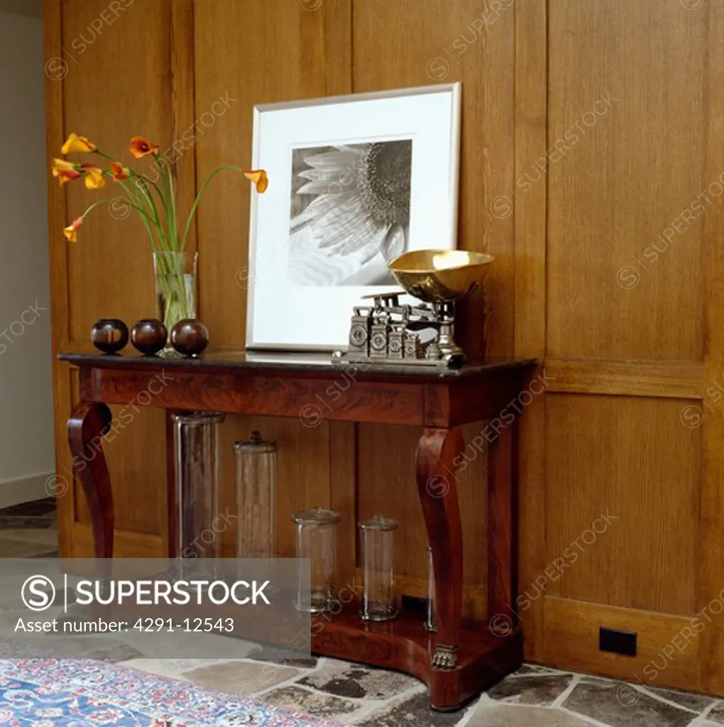 Large black and white photograph on panelled wall above old scales antique console table with glass cylinder vases
