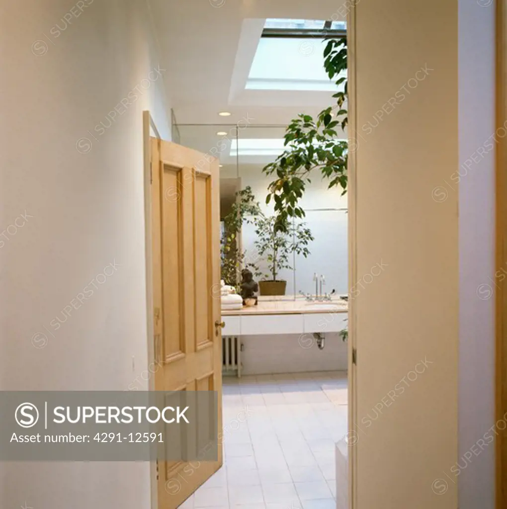 White tiled floor in modern white loft bathroom with pale wood door