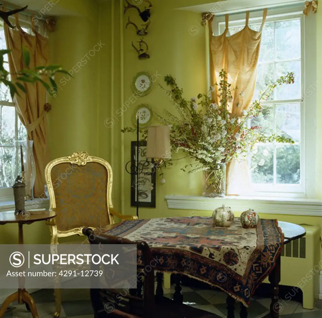 Gilt framed 18th century chair in pale green dining room with oriental rug on circular table