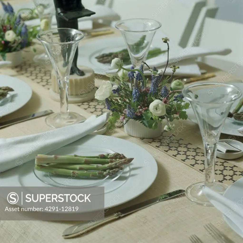 Close-up of asparagus on white plates on table set for lunch