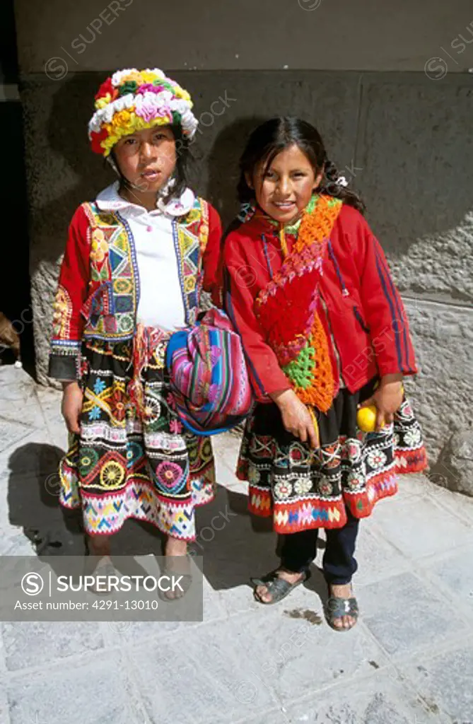 Two young girls smiling, standing in the street and wearing colourful clothing, Cusco, Peru