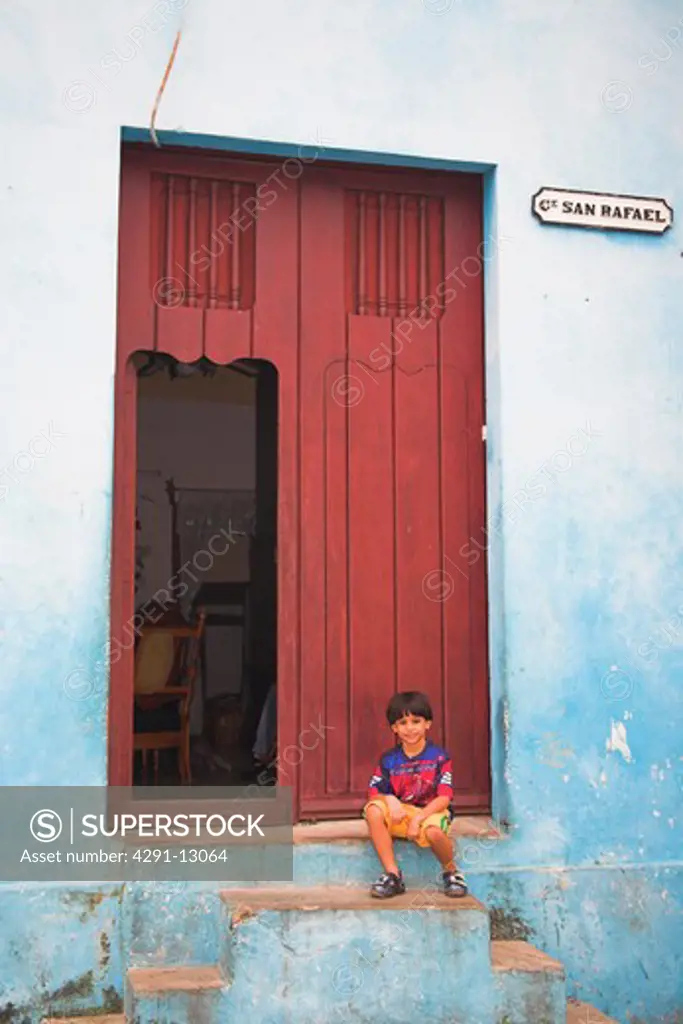 Young boy sitting on a doorstep in front of a house, Camaguey, Camaguey Province, Cuba