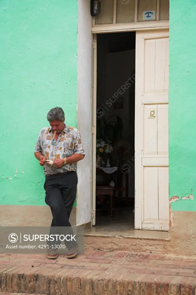 Man standing cross-legged outside a house, Trinidad, Sancti Spiritus Province, Cuba
