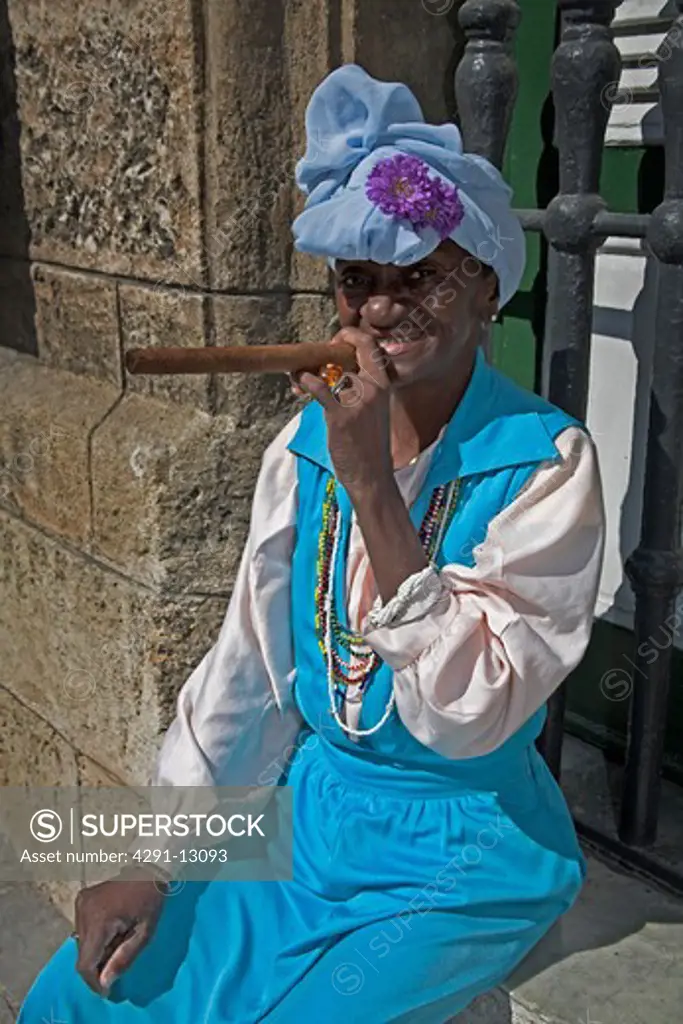 Lady wearing colourful traditional clothing, smoking a cigar, Havana, La Habana Vieja, Cuba