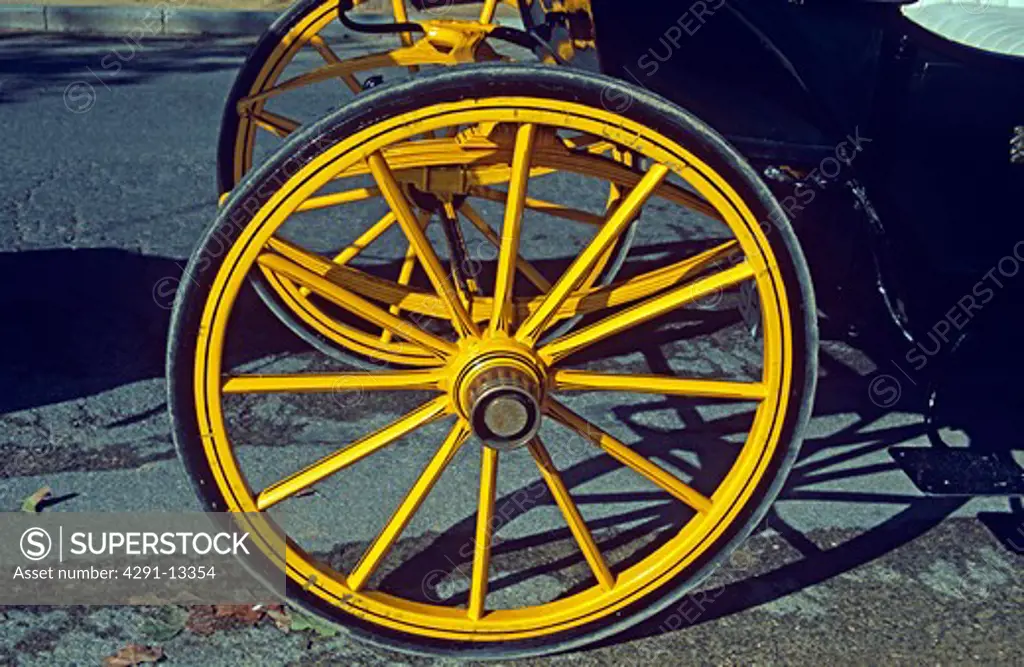Yellow brightly painted wheel of horse drawn carriage in Plaza Virgen de los Reyes, Seville, Spain