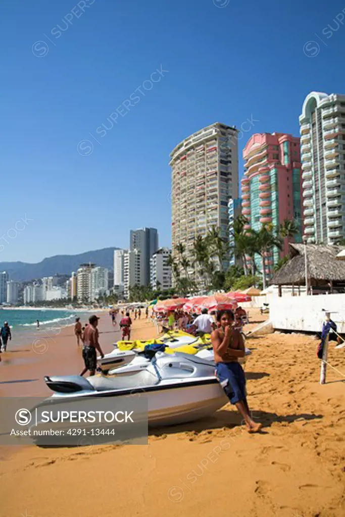 Young man with jetski on beach in front of condominiums and hotels in Acapulco, Mexico