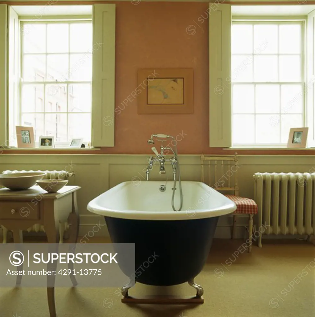Rolltop bath in the centre on pink and cream townhouse bathroom