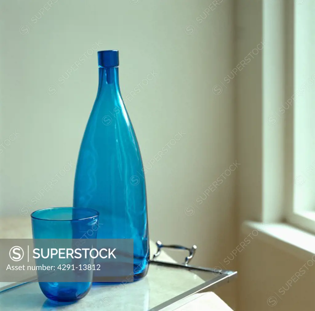 Empty blue glass bottle and glass on tray