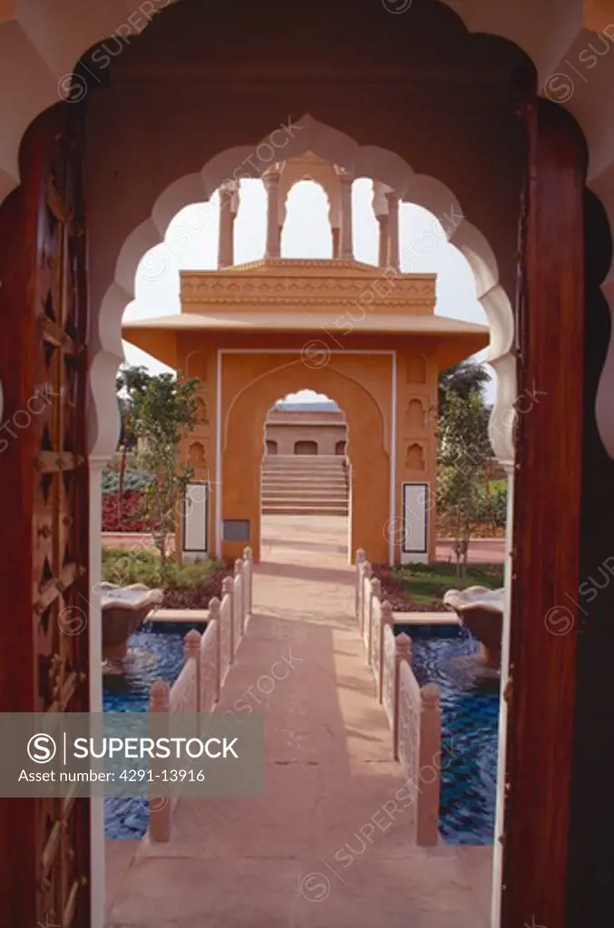 View through arched doorway to marble walkway over blue tiled pool at the Rajvilas Hotel near Jaipur in Rajastan