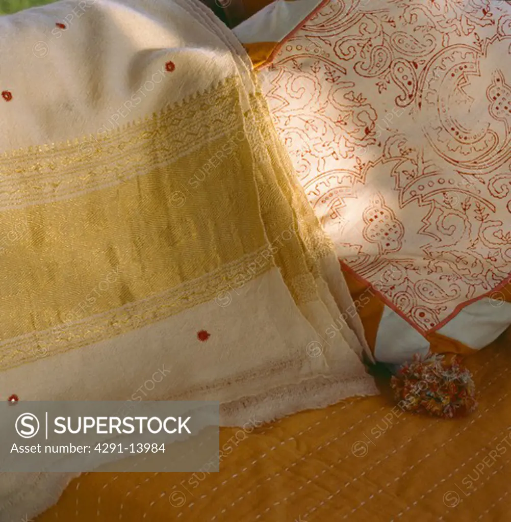 Close-up of gold-embroidered cashmere shawl and embroidered cushion