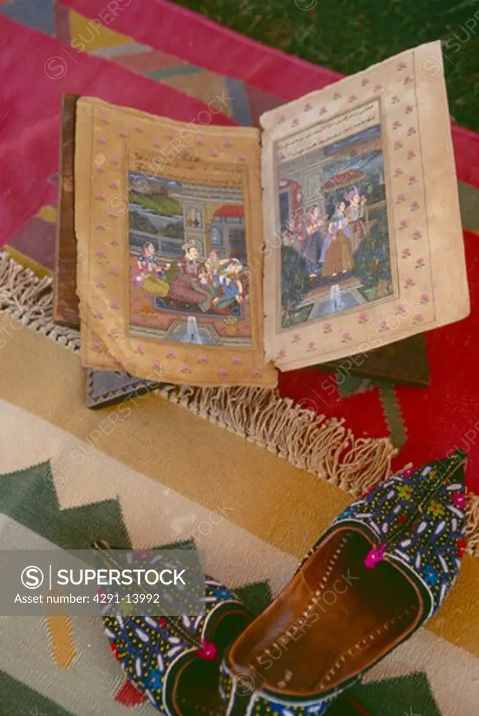 Close-up of illustrated antique Indian book and intricately embroidered Rajastani slippers