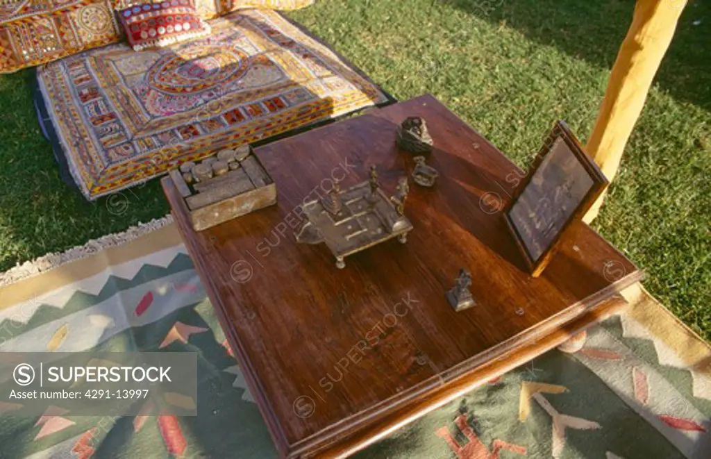 Close-up of Rajastani brass ornaments on wooden table in tent