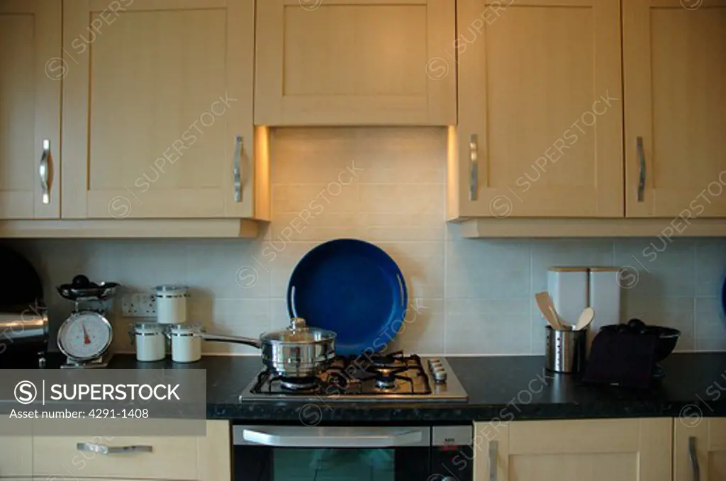 Close-up of light wood cupboards and gas hob in modern kitchen