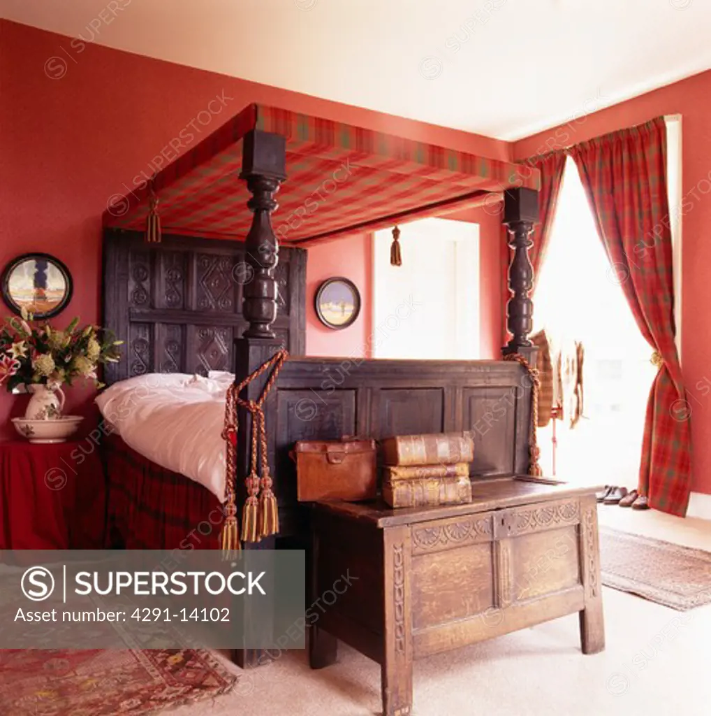 Antique chest and four-poster bed in red bedroom