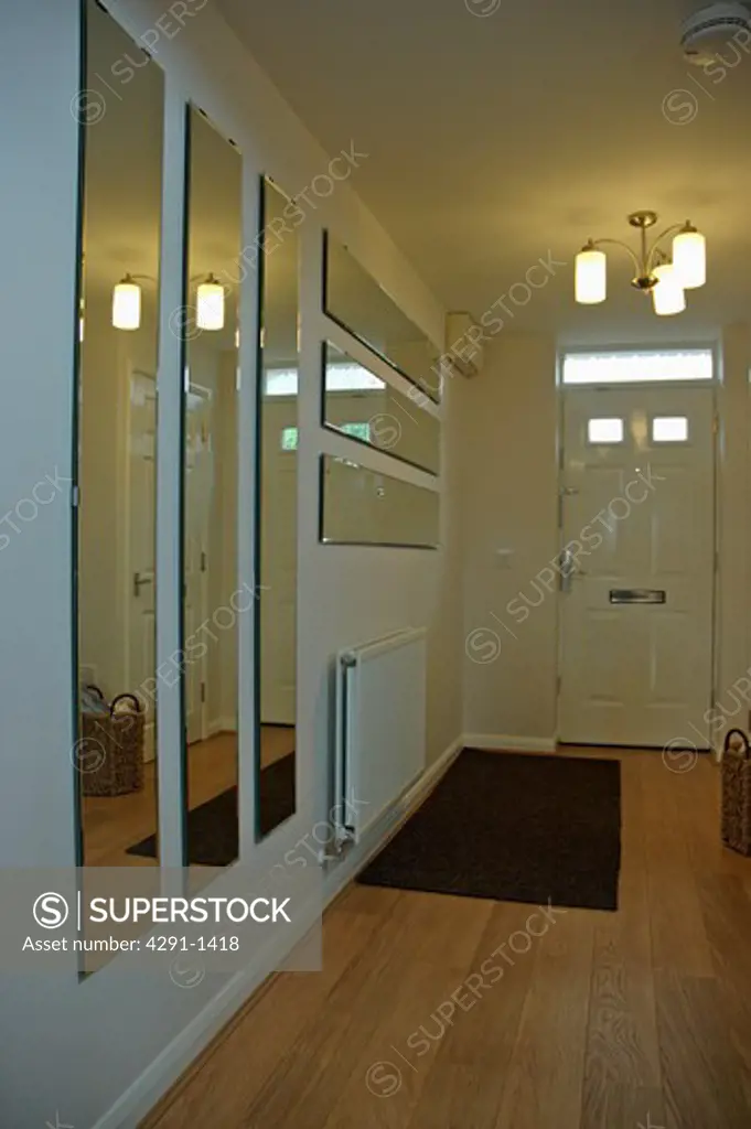 Groups of rectangular mirrors in modern white hall with wooden flooring