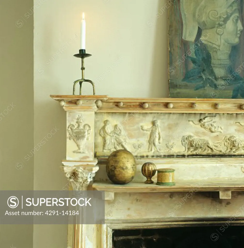 Close-up of lighted candle on classically carved marble mantelpiece