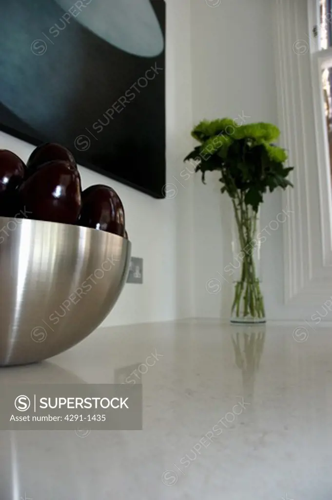 Close-up of stainless steel bowl and small flower arrangement on granite worktop