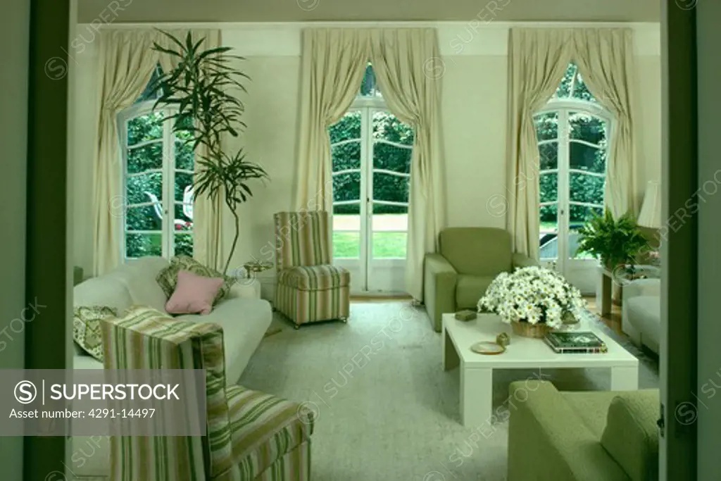 Striped chairs and cream curtains in traditional living room