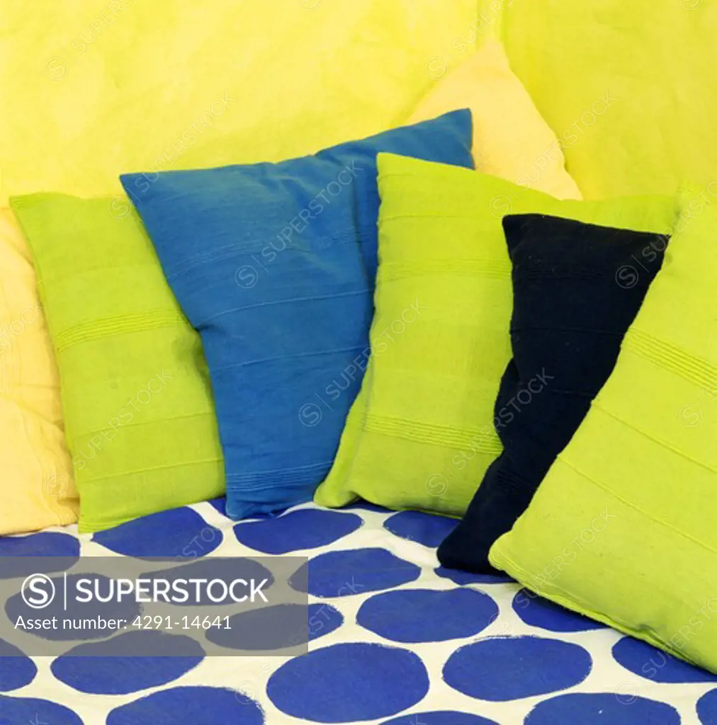 Close-up of lime-green and blue cushions on blue spotted fabric