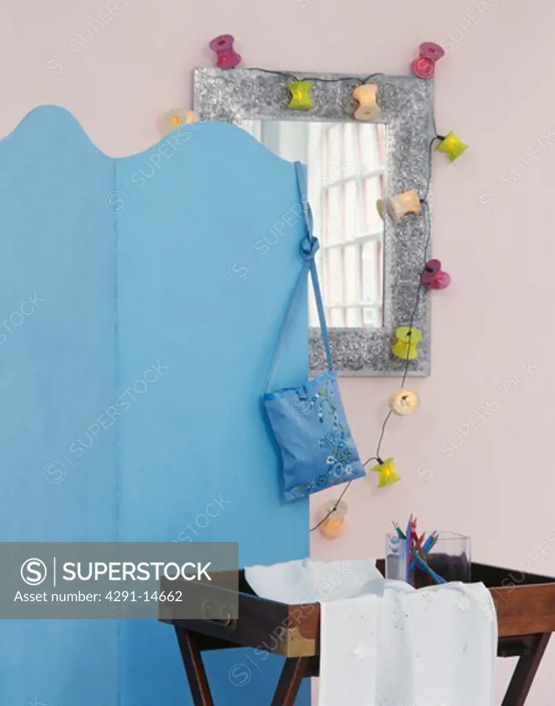Close-up of blue folding screen beside mirror with novelty fairy lights