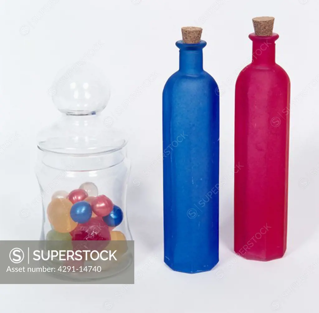 Close-up of tall red and blue bottles with lidded glass storage jar