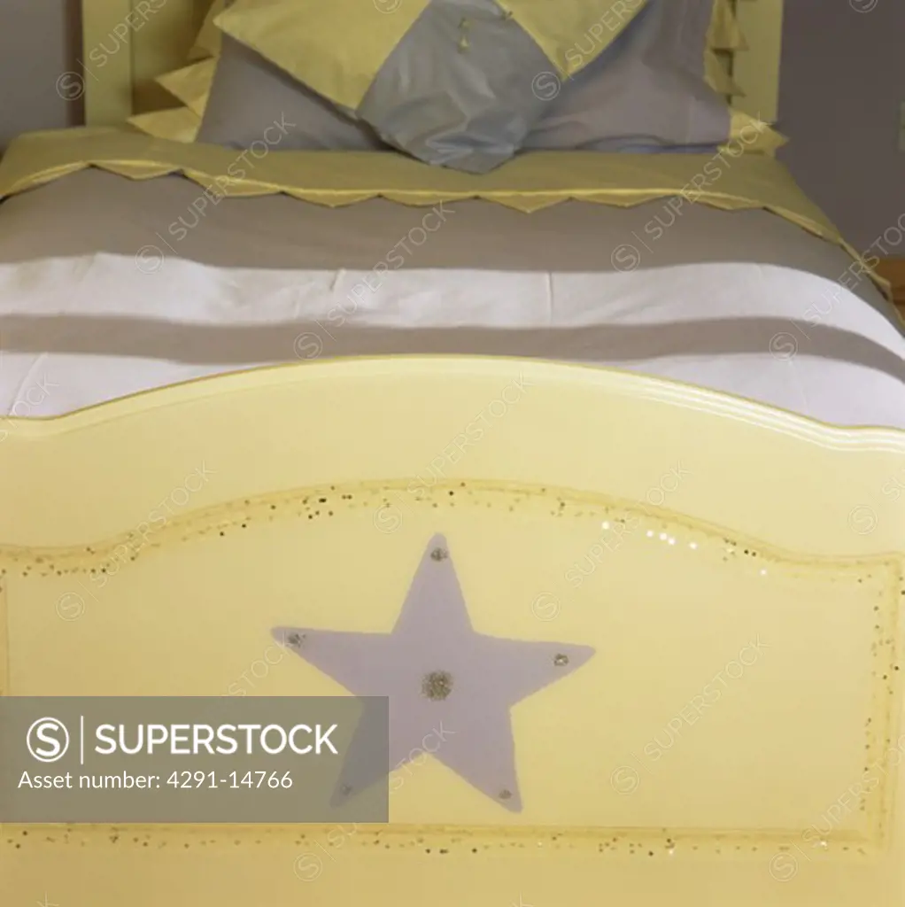 Close-up of child's star-themed wooden bed with mauve bedlinen
