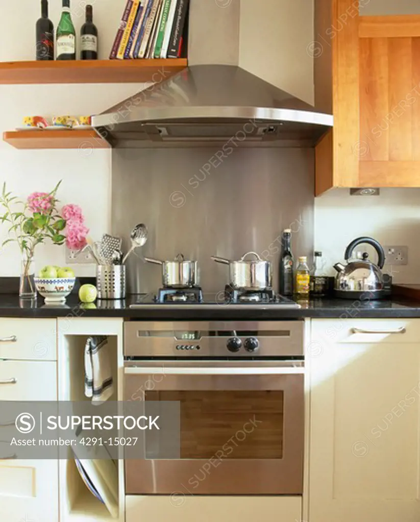 Stainless steel extractor and splashback above steel oven in modern kitchen