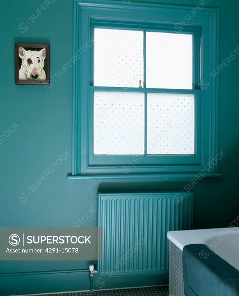 Opaque glass window above painted radiator in blue-green townhouse bathroom
