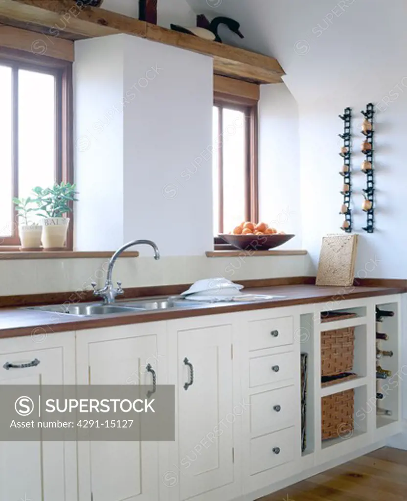 Stainless steel mixer tap and sink in granite-topped unit in modern white country kitchen